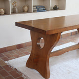 Table à manger vintage en bois massif années 60, plateau épais à chant brut, piétement traîneau sculpté, clé de tenon en croix, travail brutaliste français