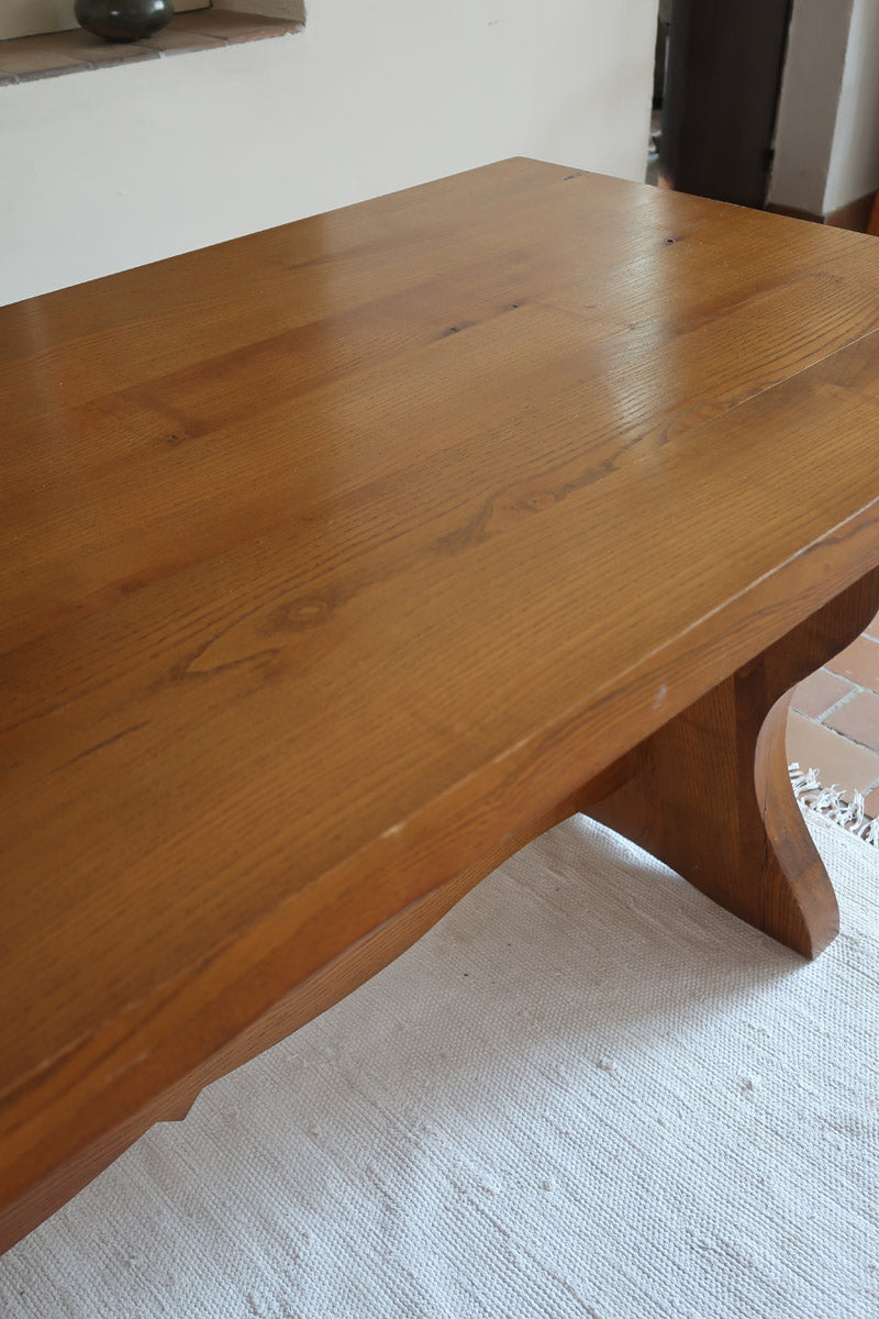 Table à manger vintage en bois massif années 60, plateau épais à chant brut, piétement traîneau sculpté, clé de tenon en croix, travail brutaliste français