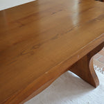 Table à manger vintage en bois massif années 60, plateau épais à chant brut, piétement traîneau sculpté, clé de tenon en croix, travail brutaliste français