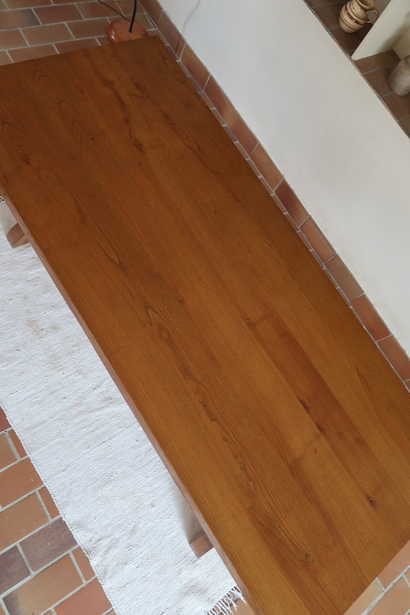 Table à manger vintage en bois massif années 60, plateau épais à chant brut, piétement traîneau sculpté, clé de tenon en croix, travail brutaliste français