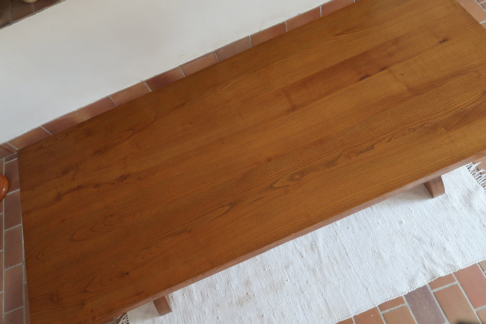 Table à manger vintage en bois massif années 60, plateau épais à chant brut, piétement traîneau sculpté, clé de tenon en croix, travail brutaliste français