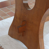 Table à manger vintage en bois massif années 60, plateau épais à chant brut, piétement traîneau sculpté, clé de tenon en croix, travail brutaliste français
