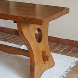 Table à manger vintage en bois massif années 60, plateau épais à chant brut, piétement traîneau sculpté, clé de tenon en croix, travail brutaliste français