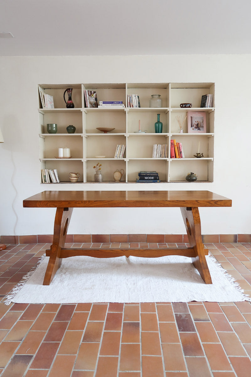 Table à manger vintage en bois massif années 60, plateau épais à chant brut, piétement traîneau sculpté, clé de tenon en croix, travail brutaliste français