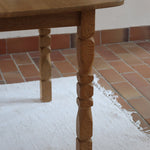 Table extensible Henning Kjærnulf en chêne massif avec pieds sculptés et deux rallonges intégrées, design danois années 60.