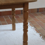 Table extensible Henning Kjærnulf en chêne massif avec pieds sculptés et deux rallonges intégrées, design danois années 60.