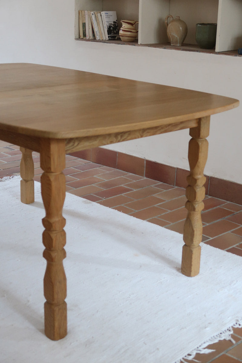 Table extensible Henning Kjærnulf en chêne massif avec pieds sculptés et deux rallonges intégrées, design danois années 60.