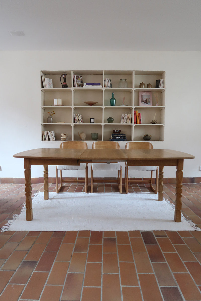 Table extensible Henning Kjærnulf en chêne massif avec pieds sculptés et deux rallonges intégrées, design danois années 60.