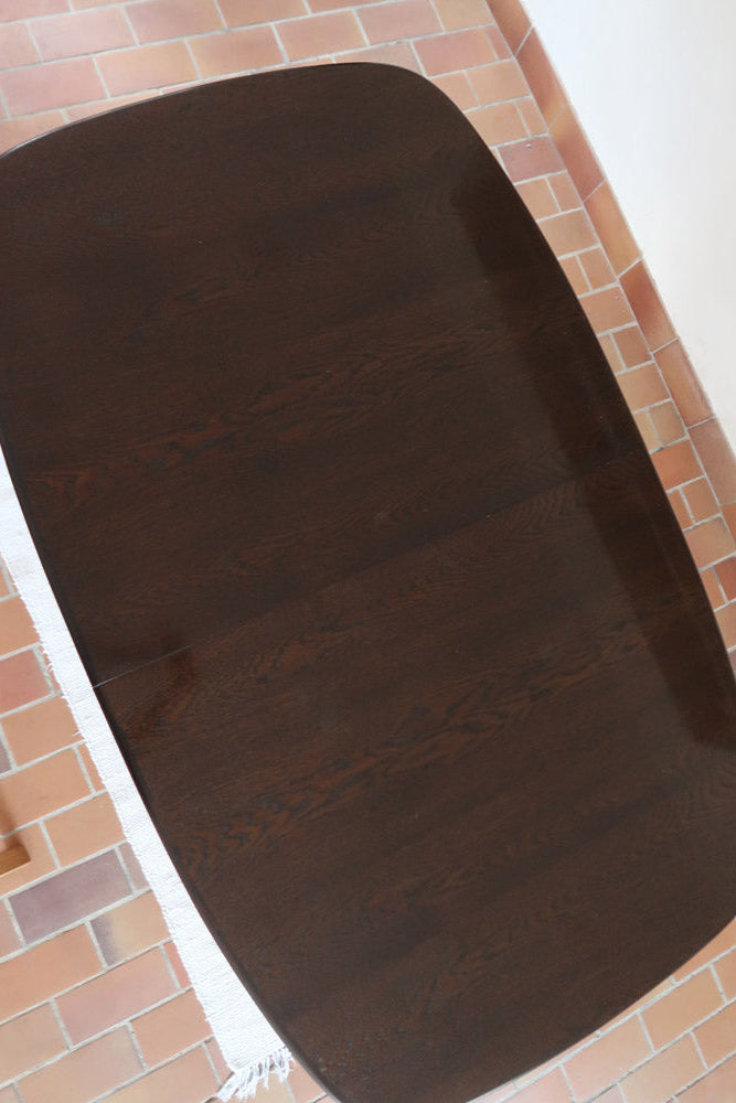 Table à manger Skovby en teck foncé avec plateau noir, piétement traîneau et deux rallonges, design danois des années 70.