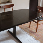 Table à manger Skovby en teck foncé avec plateau noir, piétement traîneau et deux rallonges, design danois des années 70.