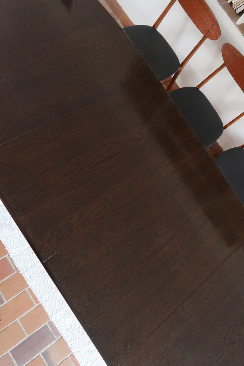 Table à manger Skovby en teck foncé avec plateau noir, piétement traîneau et deux rallonges, design danois des années 70.