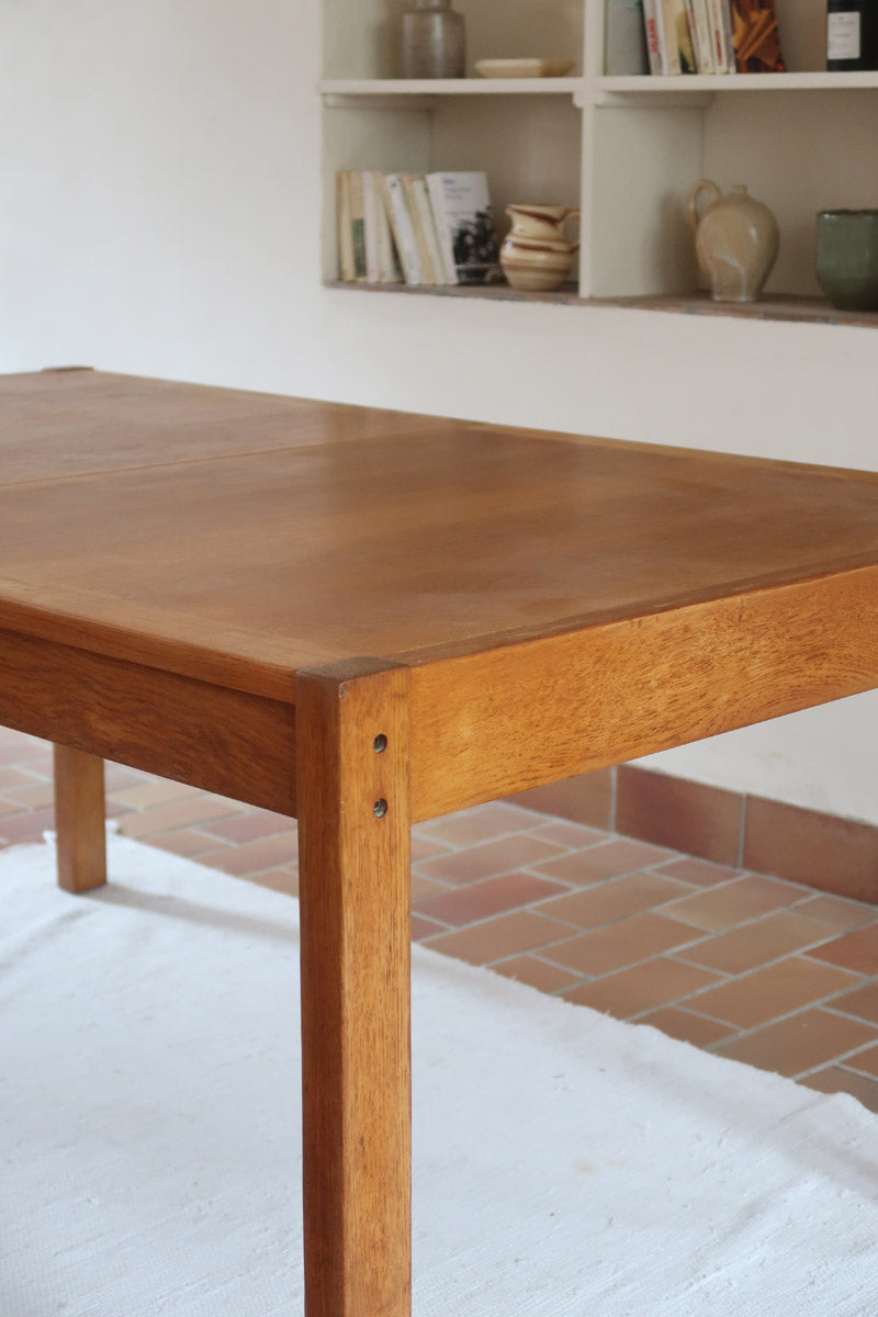 Table à manger extensible en bois massif années 60 avec deux rallonges intégrées sous le plateau.