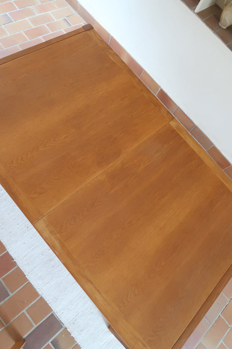 Table à manger extensible en bois massif années 60 avec deux rallonges intégrées sous le plateau.