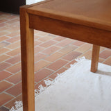 Table à manger extensible en bois massif années 60 avec deux rallonges intégrées sous le plateau.