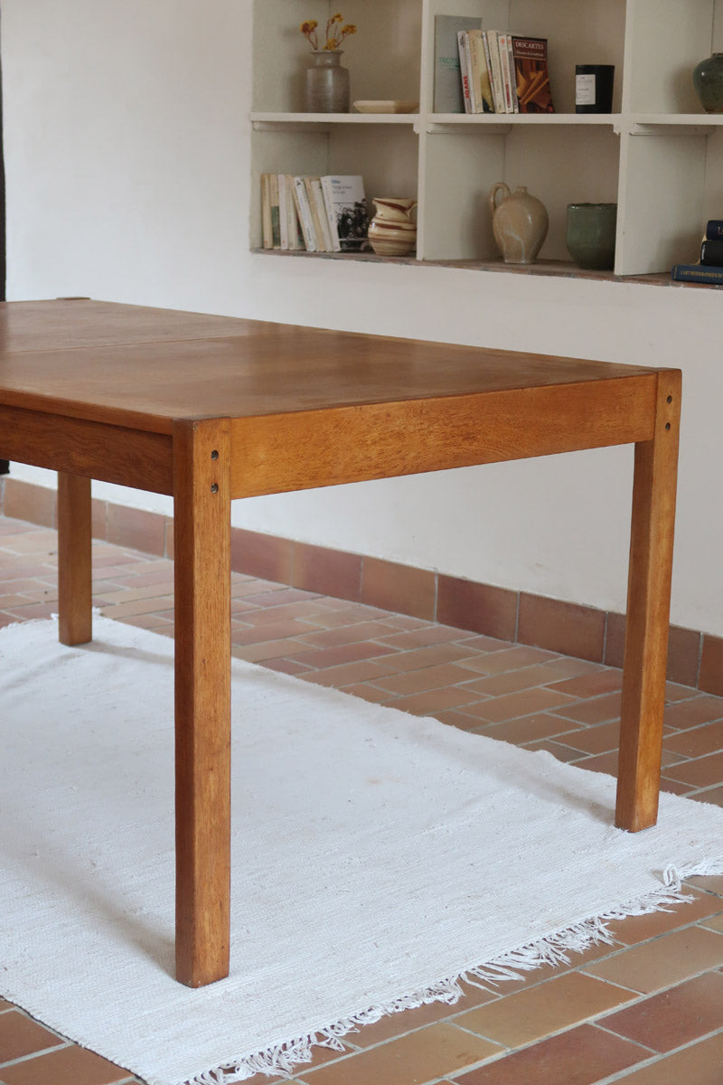 Table à manger extensible en bois massif années 60 avec deux rallonges intégrées sous le plateau.
