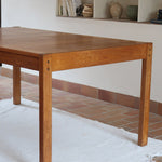 Table à manger extensible en bois massif années 60 avec deux rallonges intégrées sous le plateau.