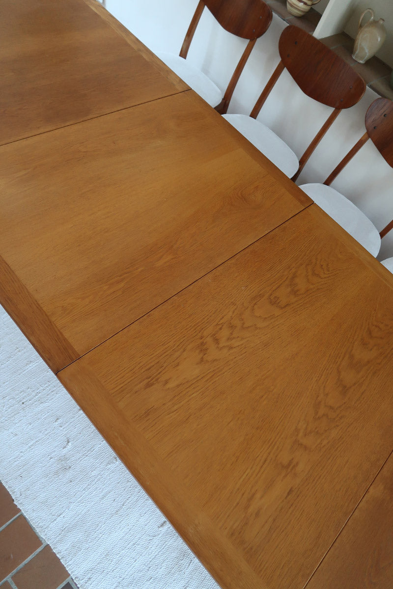 Table à manger extensible en bois massif années 60 avec deux rallonges intégrées sous le plateau.