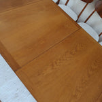 Table à manger extensible en bois massif années 60 avec deux rallonges intégrées sous le plateau.