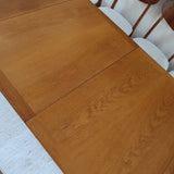 Table à manger extensible en bois massif années 60 avec deux rallonges intégrées sous le plateau.