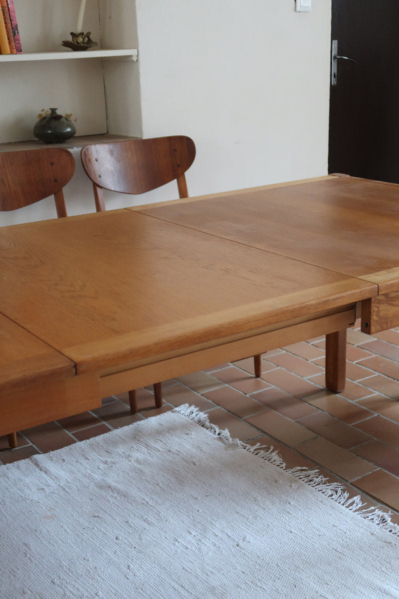 Table à manger extensible en bois massif années 60 avec deux rallonges intégrées sous le plateau.