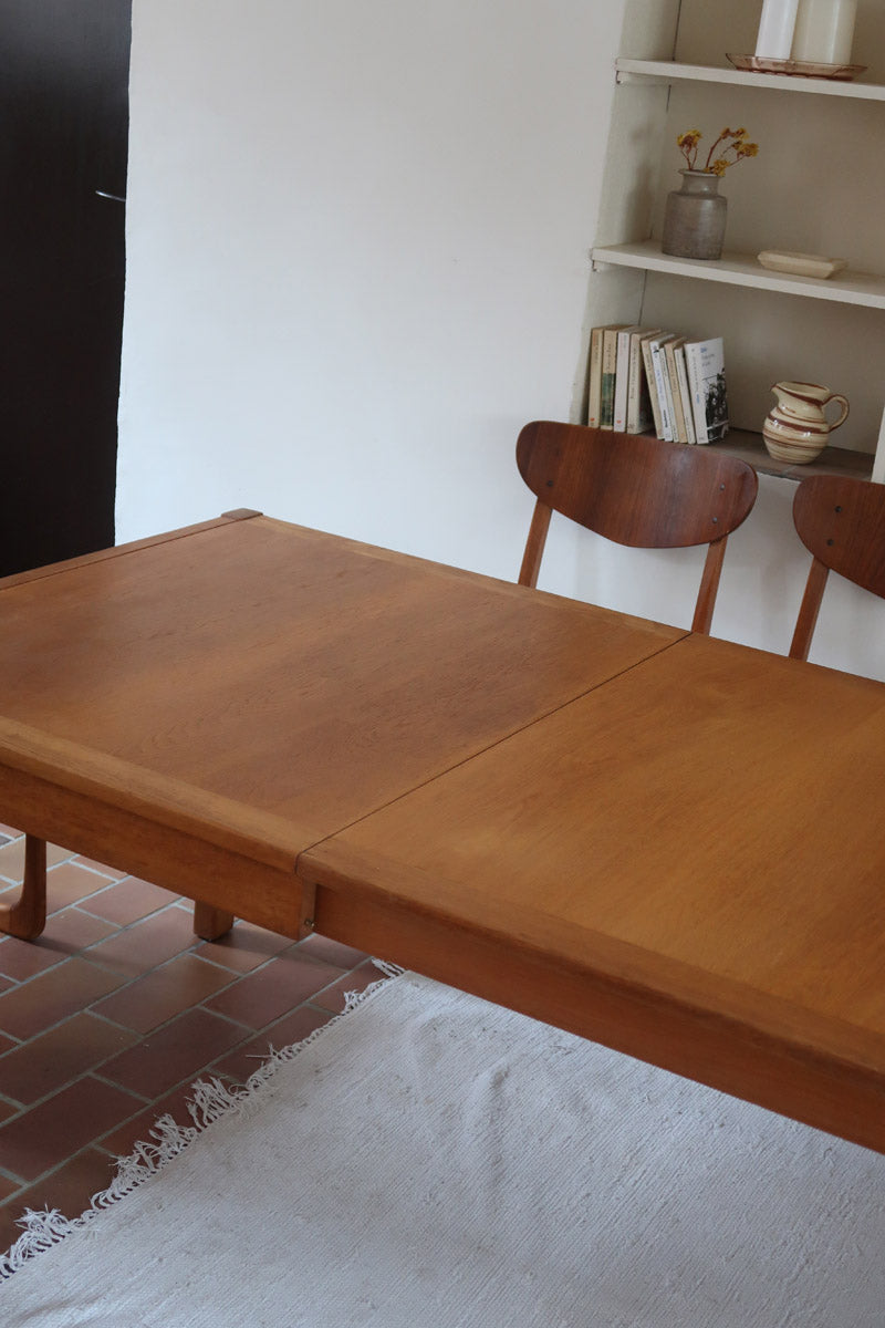 Table à manger extensible en bois massif années 60 avec deux rallonges intégrées sous le plateau.