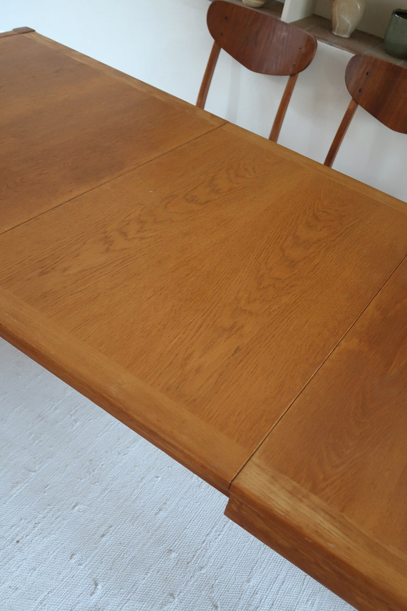 Table à manger extensible en bois massif années 60 avec deux rallonges intégrées sous le plateau.