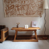 Table basse en bois massif rustique avec plateau épais et piètement trapézoïdal, style brutaliste années 50.
