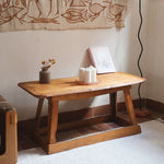 Table basse en bois massif rustique avec plateau épais et piètement trapézoïdal, style brutaliste années 50.