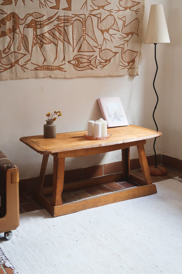 Table basse en bois massif rustique avec plateau épais et piètement trapézoïdal, style brutaliste années 50.