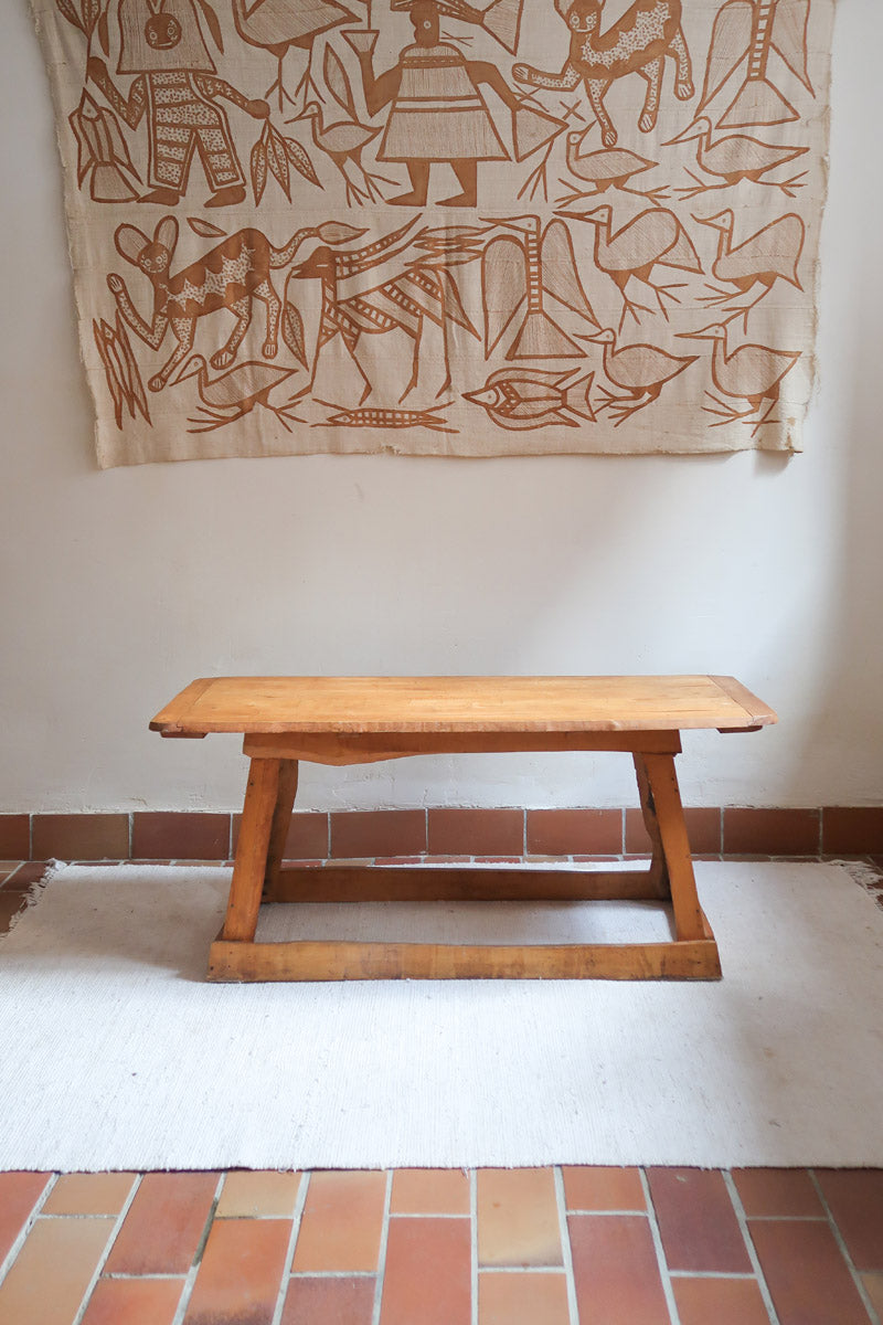 Table basse en bois massif rustique avec plateau épais et piètement trapézoïdal, style brutaliste années 50.