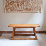 Table basse en bois massif rustique avec plateau épais et piètement trapézoïdal, style brutaliste années 50.