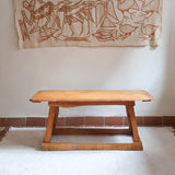 Table basse en bois massif rustique avec plateau épais et piètement trapézoïdal, style brutaliste années 50.