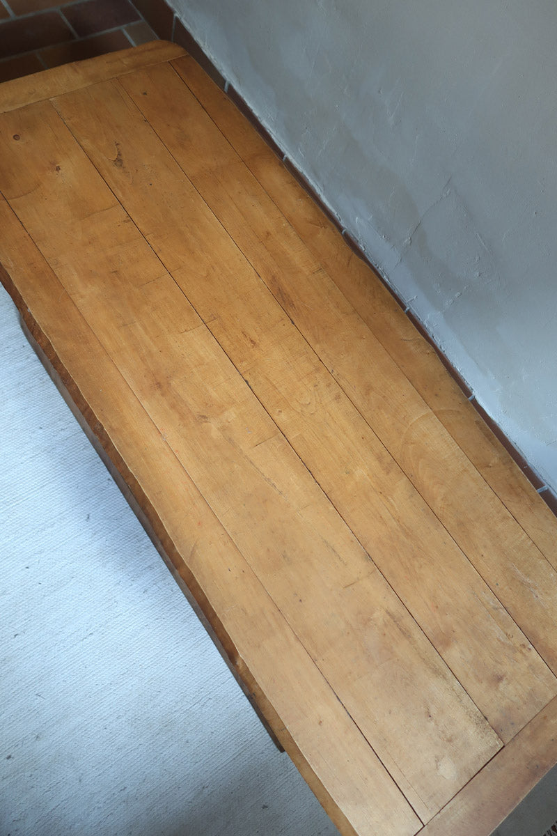 Table basse en bois massif rustique avec plateau épais et piètement trapézoïdal, style brutaliste années 50.