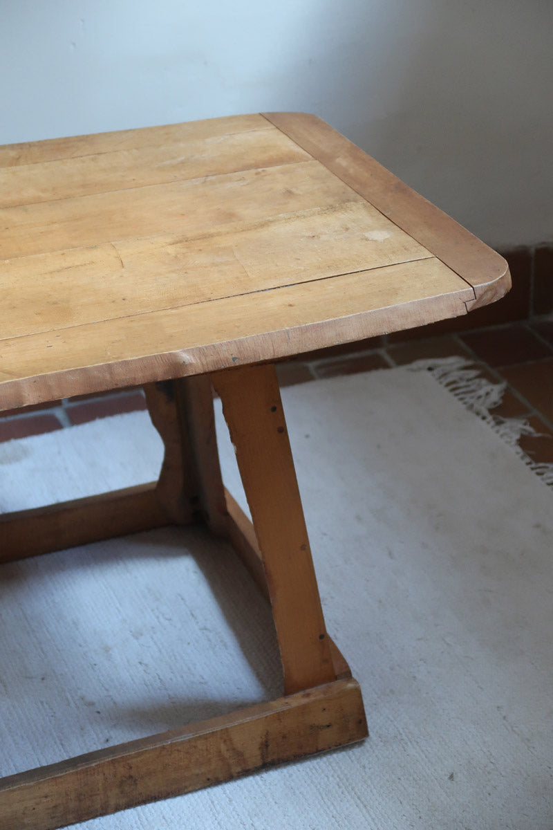 Table basse en bois massif rustique avec plateau épais et piètement trapézoïdal, style brutaliste années 50.