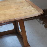 Table basse en bois massif rustique avec plateau épais et piètement trapézoïdal, style brutaliste années 50.