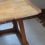 Table basse en bois massif rustique avec plateau épais et piètement trapézoïdal, style brutaliste années 50.
