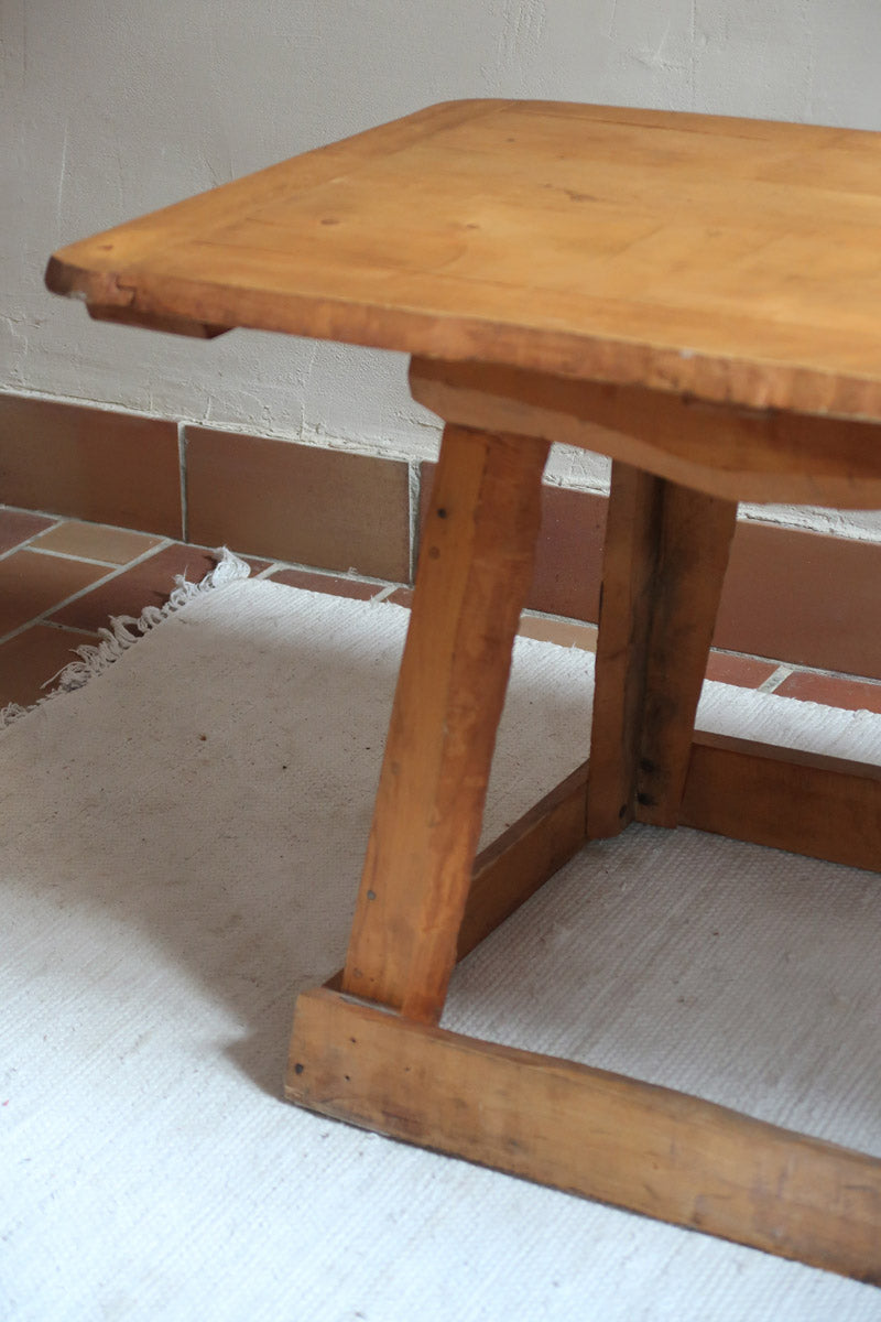 Table basse en bois massif rustique avec plateau épais et piètement trapézoïdal, style brutaliste années 50.