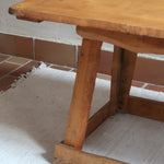 Table basse en bois massif rustique avec plateau épais et piètement trapézoïdal, style brutaliste années 50.