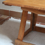 Table basse en bois massif rustique avec plateau épais et piètement trapézoïdal, style brutaliste années 50.