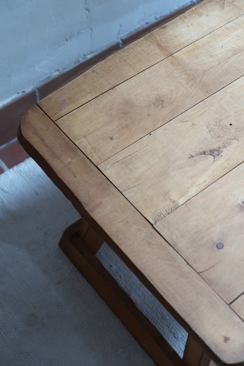Table basse en bois massif rustique avec plateau épais et piètement trapézoïdal, style brutaliste années 50.