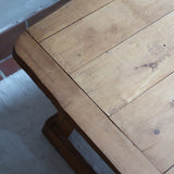 Table basse en bois massif rustique avec plateau épais et piètement trapézoïdal, style brutaliste années 50.