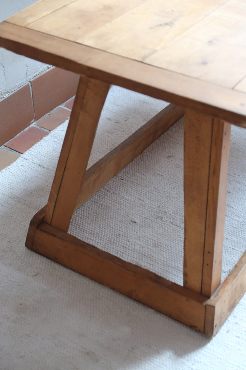 Table basse en bois massif rustique avec plateau épais et piètement trapézoïdal, style brutaliste années 50.