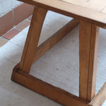 Table basse en bois massif rustique avec plateau épais et piètement trapézoïdal, style brutaliste années 50.