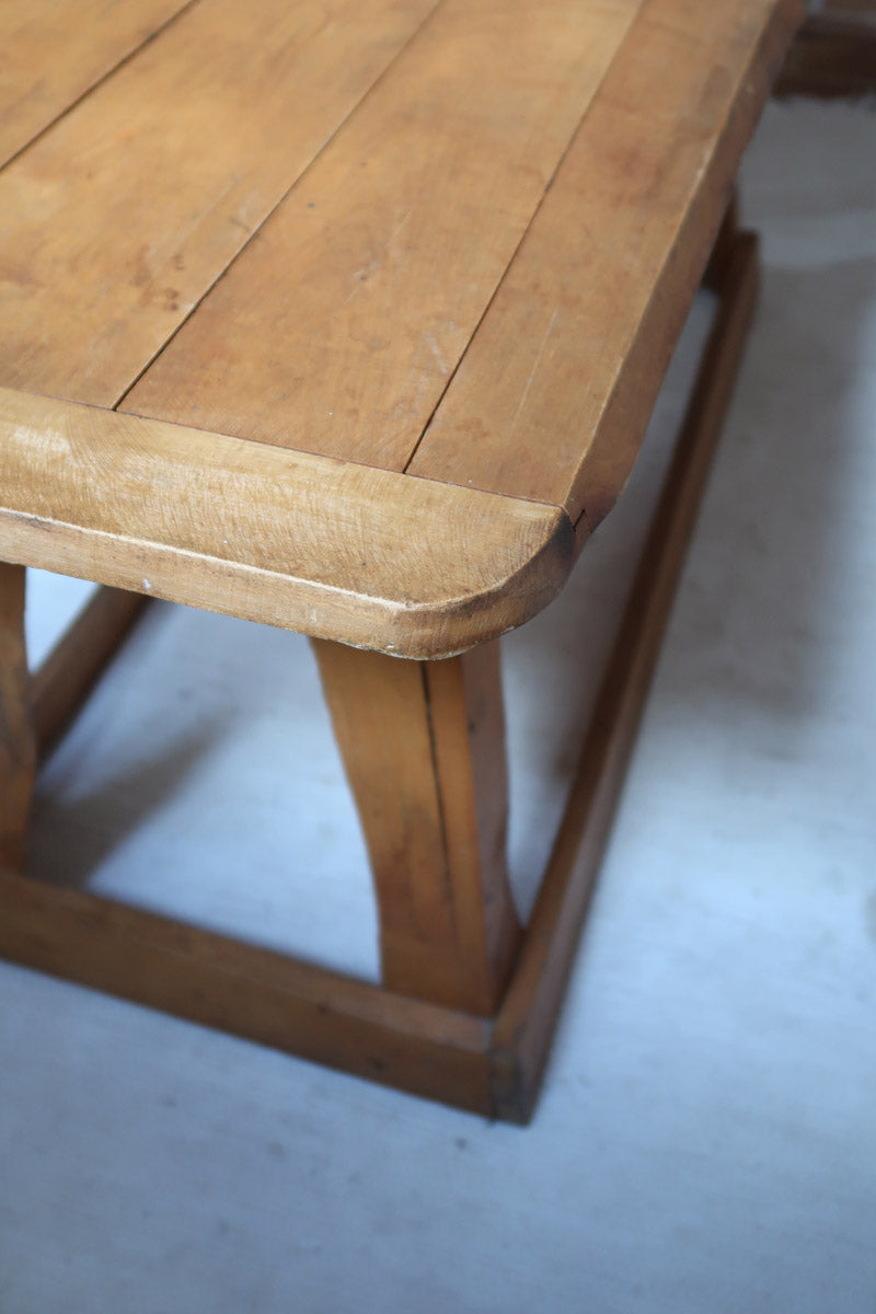 Table basse en bois massif rustique avec plateau épais et piètement trapézoïdal, style brutaliste années 50.