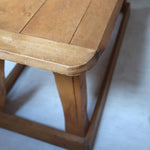 Table basse en bois massif rustique avec plateau épais et piètement trapézoïdal, style brutaliste années 50.