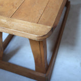 Table basse en bois massif rustique avec plateau épais et piètement trapézoïdal, style brutaliste années 50.