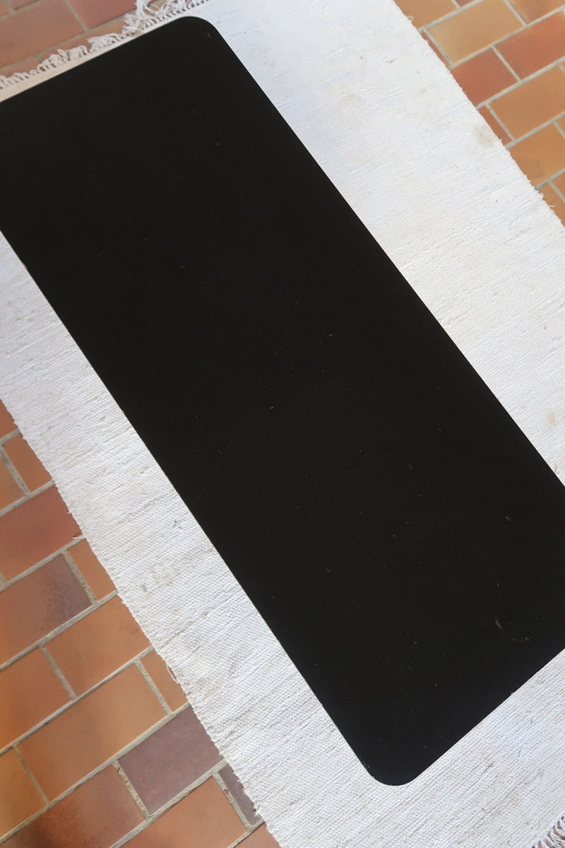 Table basse design années 70 avec plateau noir rectangulaire et piétement en acier brossé en forme de patins.