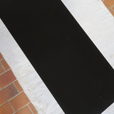 Table basse design années 70 avec plateau noir rectangulaire et piétement en acier brossé en forme de patins.