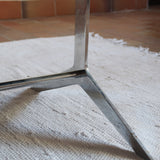 Table basse design années 70 avec plateau noir rectangulaire et piétement en acier brossé en forme de patins.