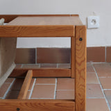 Table basse vintage en pin massif années 70, structure cubique chevillée, porte-revues en toile écrue suspendu sous le plateau, esprit Maison Regain